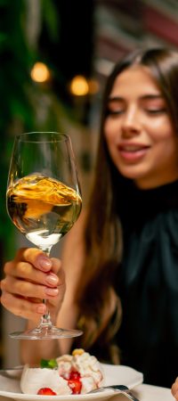 Close-up of a cute young girl drinking expensive delicious wine during a date in Italian restaurant